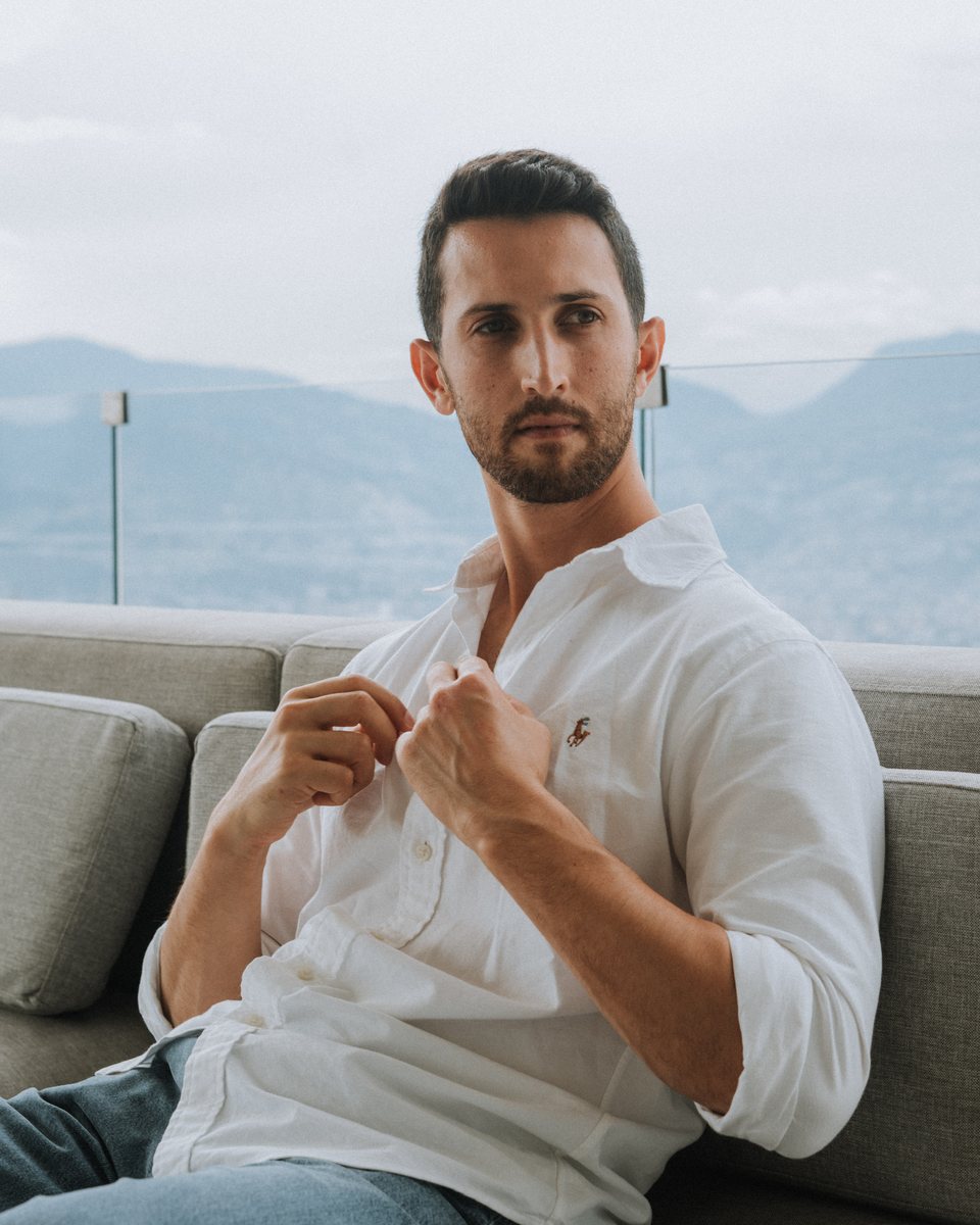 Daniel Jacob, founder of Everlasting Confidence, sitting on a sofa in a white shirt with mountains behind him.
